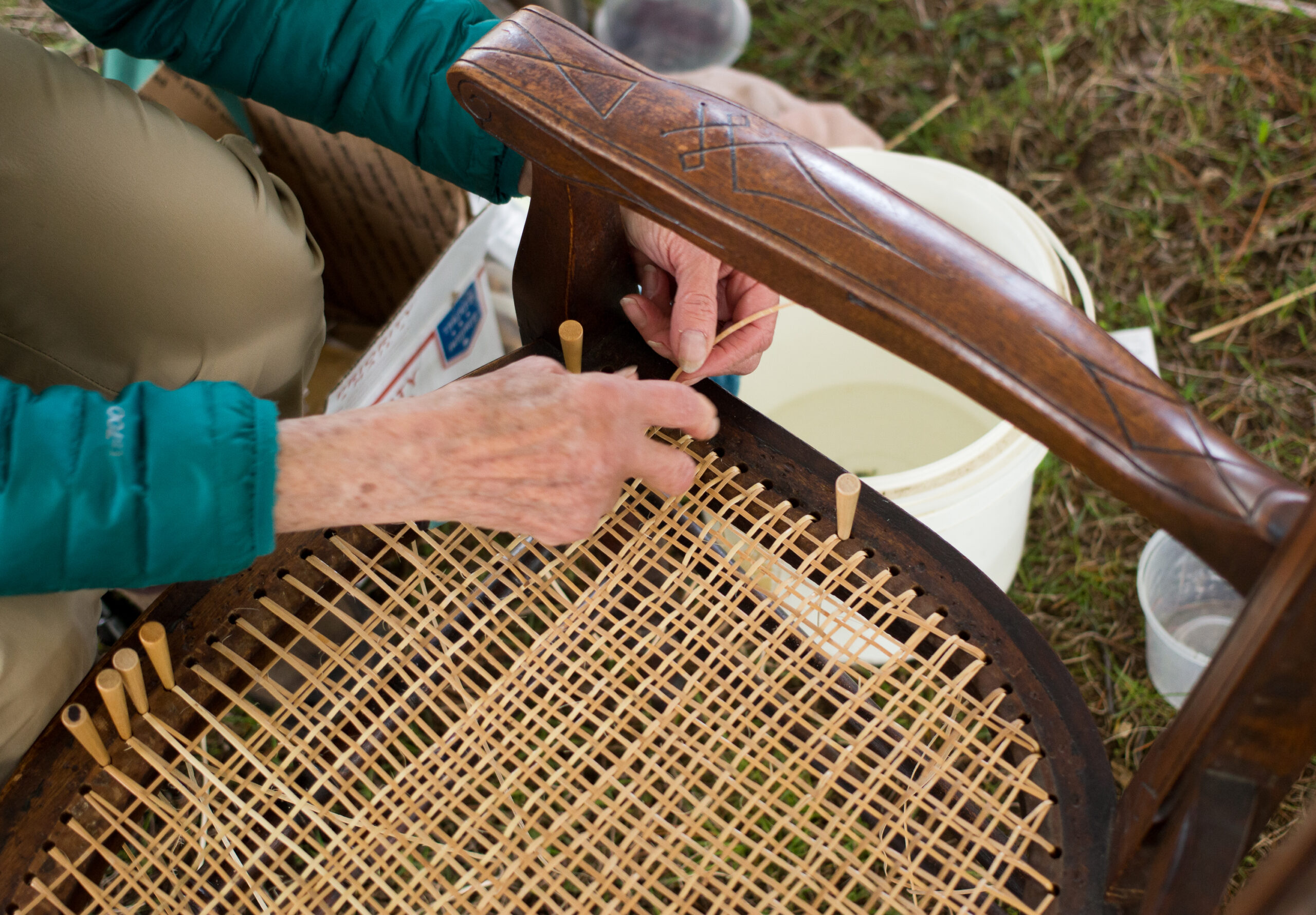 Woman repairs chair by caning the seat during Memorial Day Weekend at The Greater Rochester Heritage Days Festival.