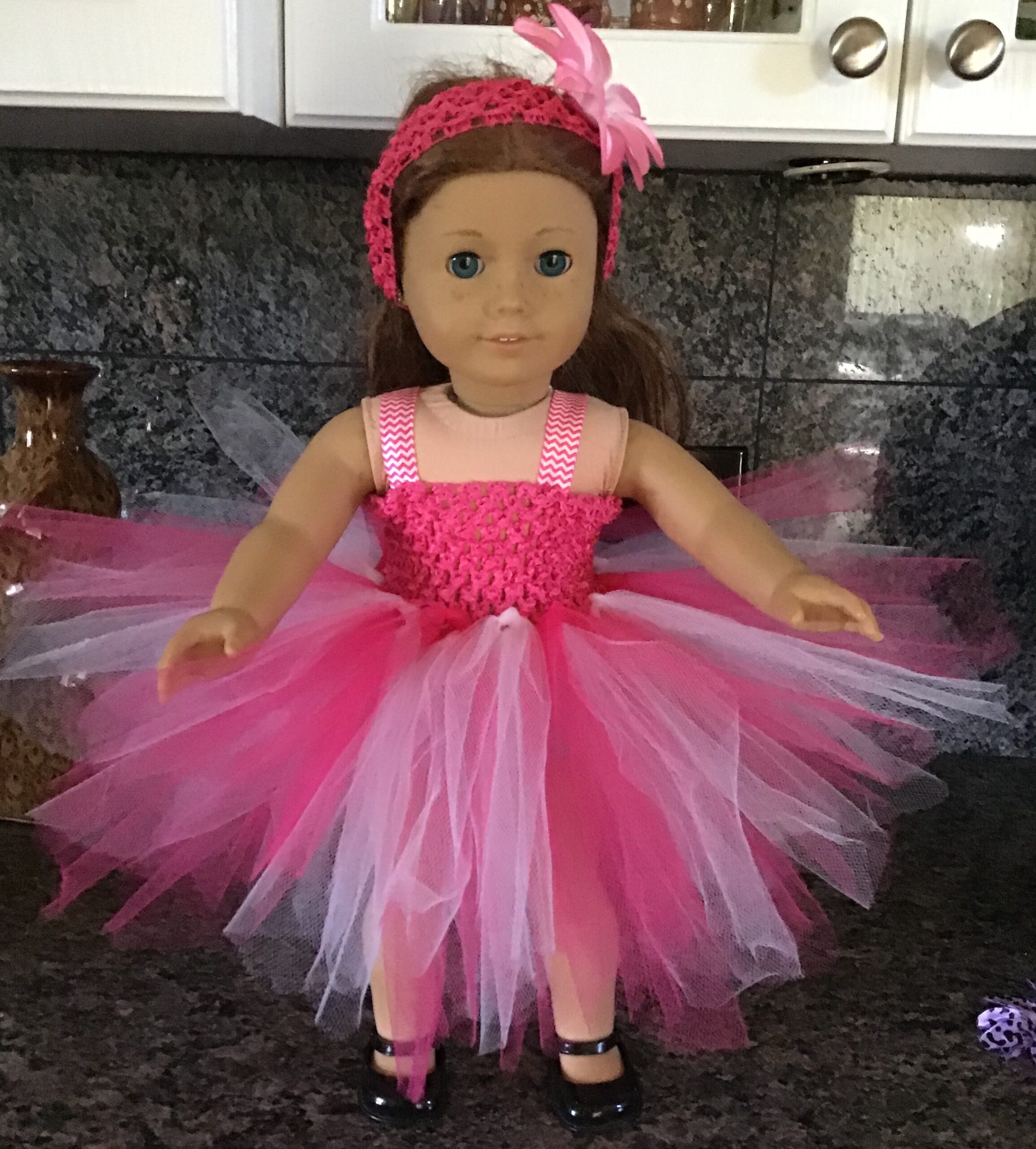 Doll wearing extremely pink and fluffy dress with headband and bow. Doll clothing can be found at The Greater Rochester Heritage Days Festival.