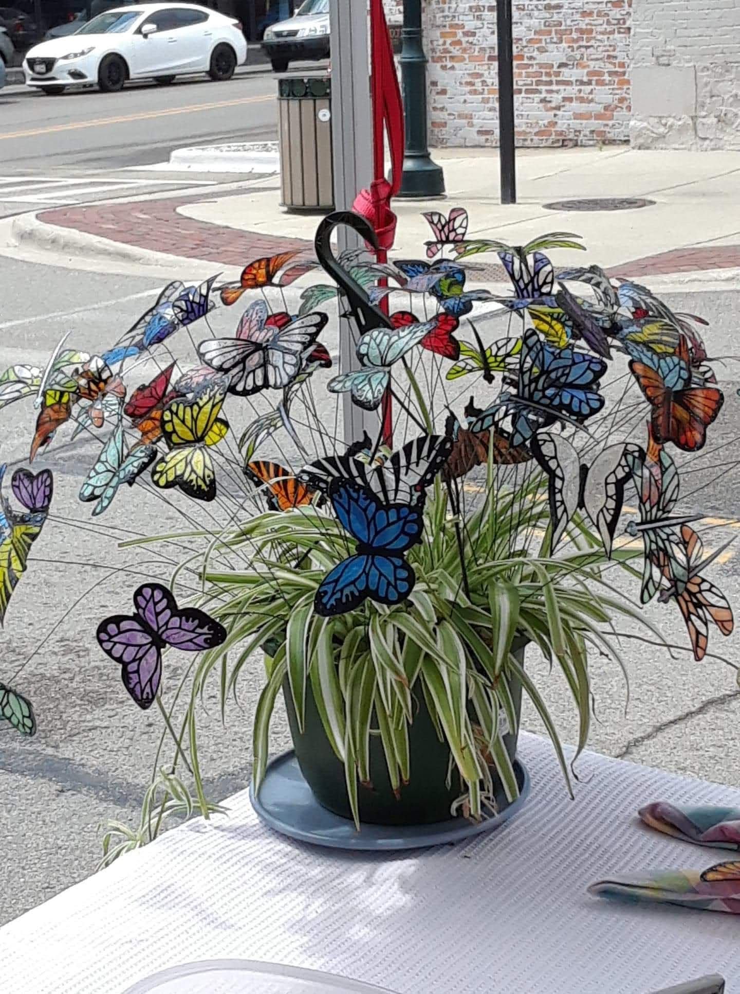 Multi-colored plastic butterflies on stiff wires in a planter on a table. Handmade by "My Dad's Butterflies"