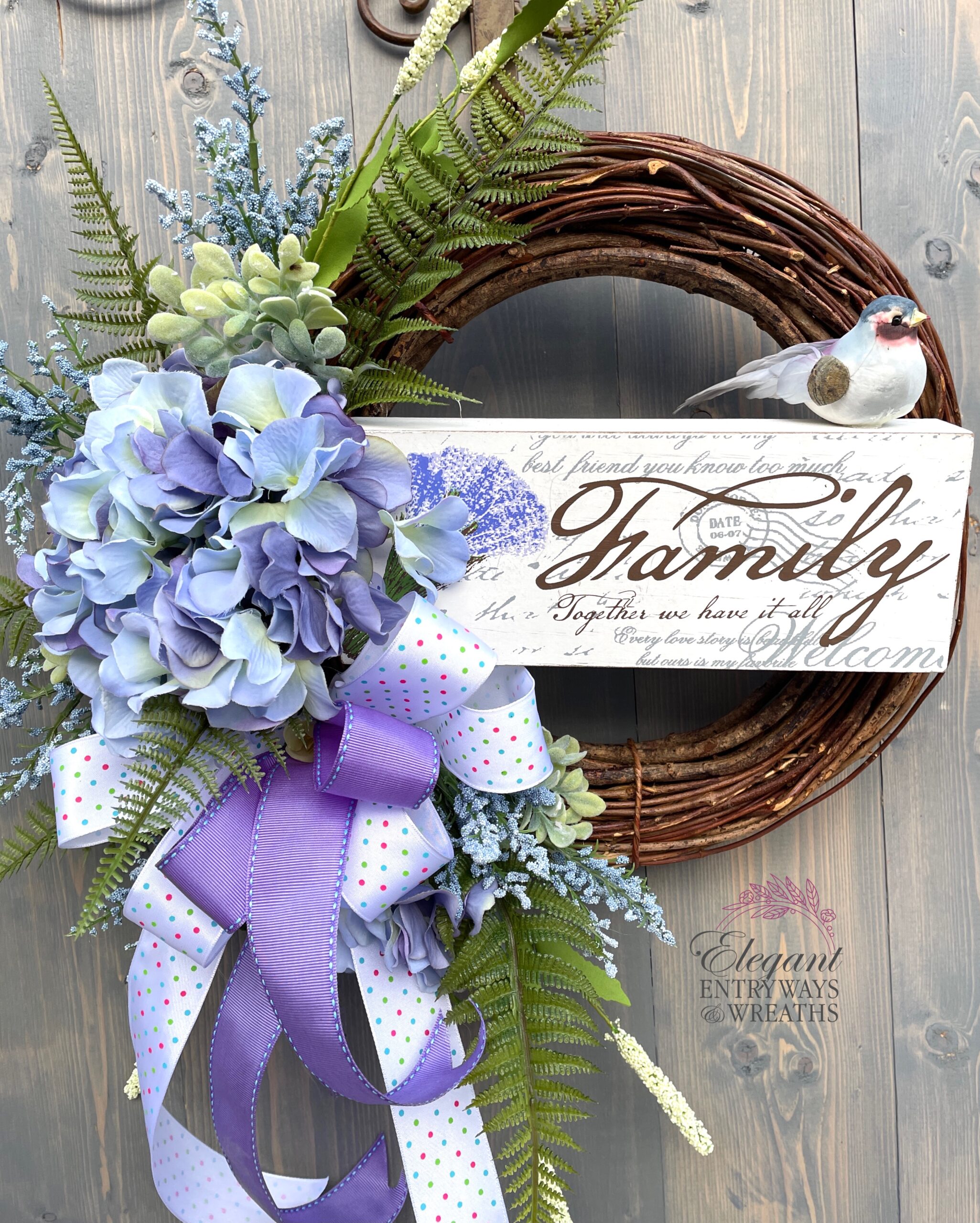 Wreath with purple ribbon, a bird, and a sign that says "family".